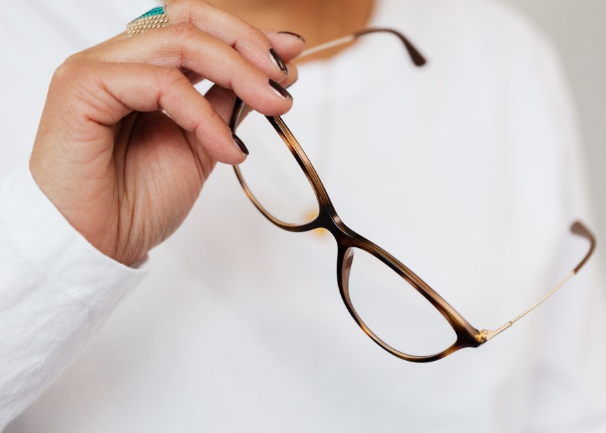 Person, die eine Brille in der Hand hält