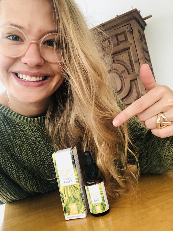 Zufriedene Kundin zeigt NATURTREU Sonnenfreund Vitamin D3 K2 Tropfen. 